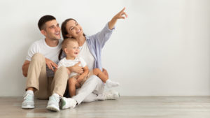 Important Ways To Protect Yourself and Your Family 7 Happy Young Family With Infant Baby Sitting On Floor And Pointing Aside